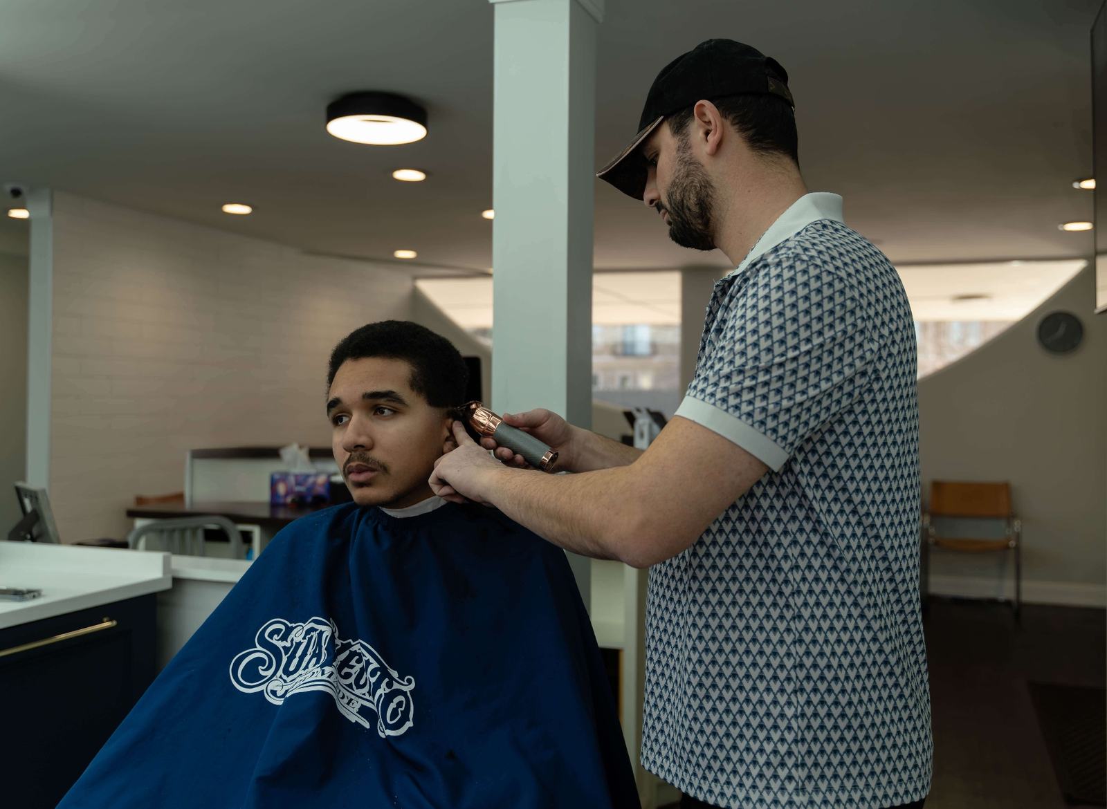 Barber trimming client hair with professional clippers at Cherry Barbers barbershop Cherry Creek Denver CO