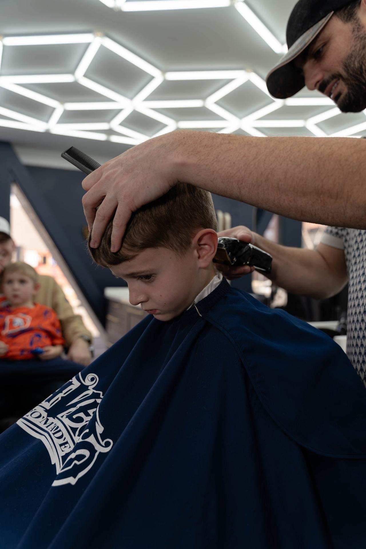 Barber cutting kids hair with clippers at Cherry Barbers family barbershop Denver Colorado